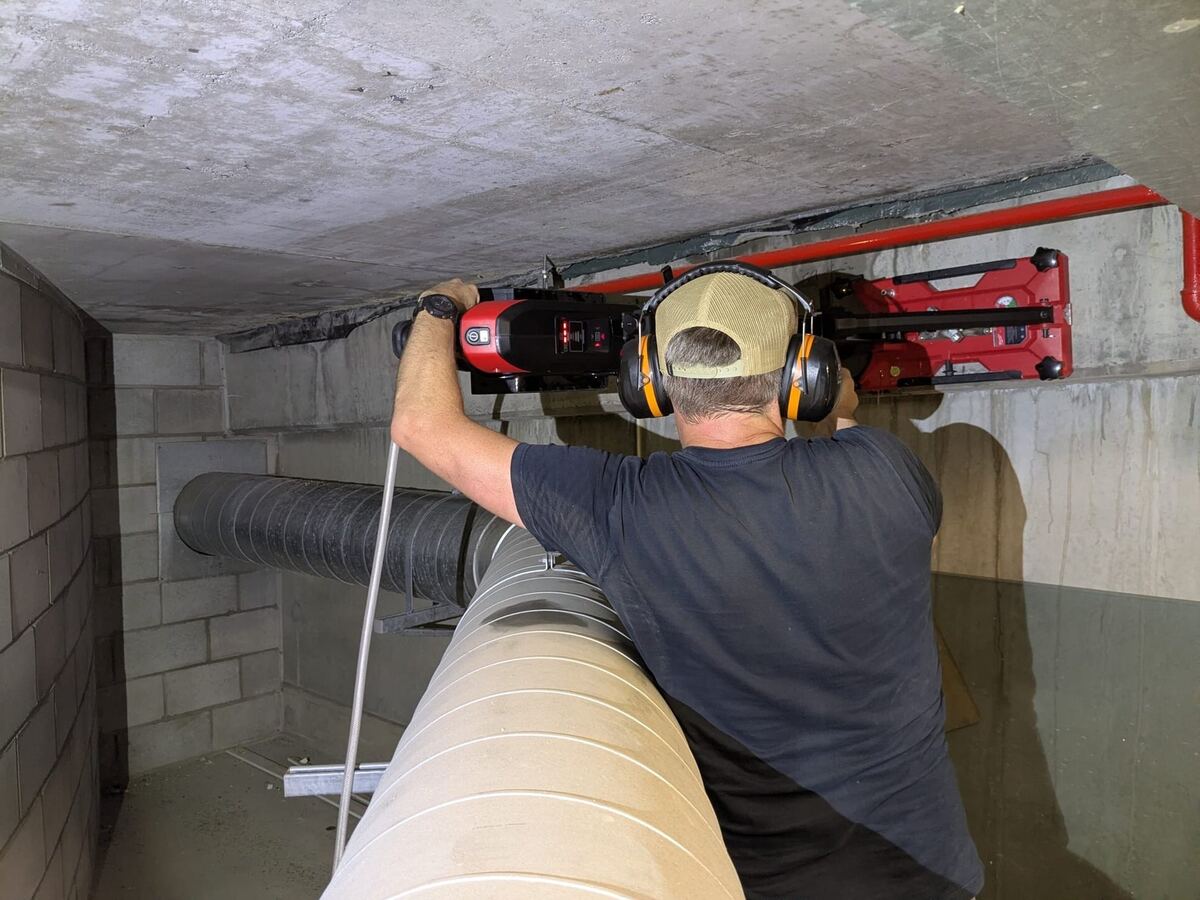 SiteOps technician performing concrete core extraction in building soffit